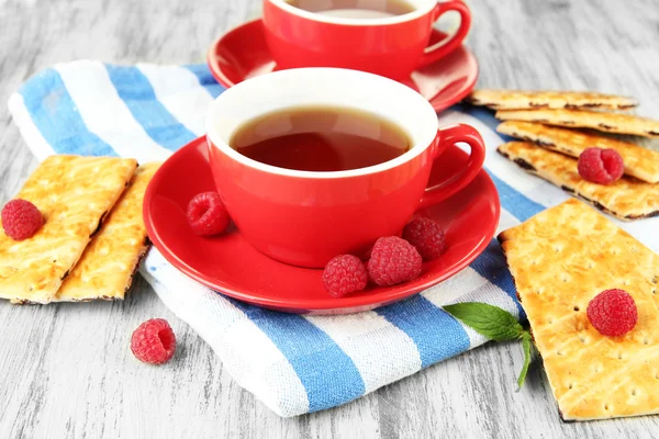 Kopjes thee met koekjes en frambozen op tabel close-up — Stockfoto