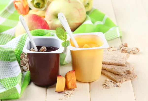 Sobremesas de creme saborosas com pedaços de frutas frescas, biscoitos e flocos, na cor de fundo de madeira — Fotografia de Stock