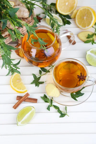 Waterkoker en kopje thee met gember op houten tafel — Stockfoto