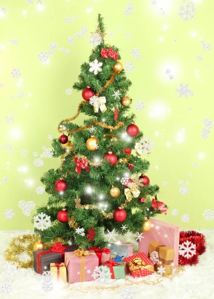 Decorated Christmas tree with gifts on green wall background — Stock Photo, Image