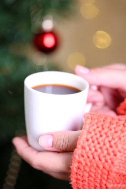 Kupa tutan eller sıcak içecek, Noel ağacı arka plan üzerinde yakın çekim