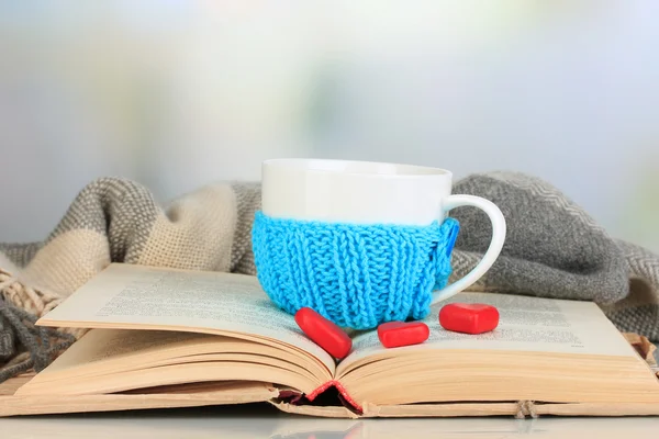 Tasse mit Stricksachen darauf und aufgeschlagenem Buch in Nahaufnahme — Stockfoto