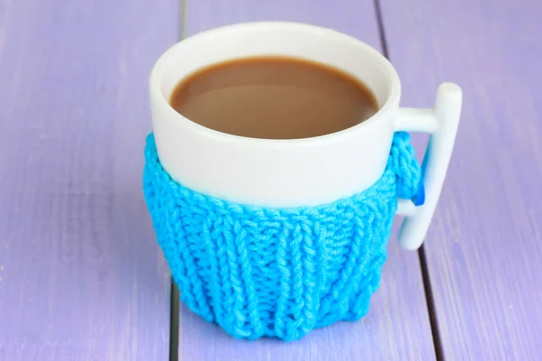 Cup with knitted thing on it on wooden table close up — Stock Photo, Image