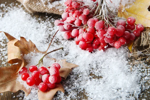 Κόκκινα μούρα viburnum και χιόνι σε χαρτοπετσέτα λινάτσα, σε ξύλινο φόντο — Φωτογραφία Αρχείου