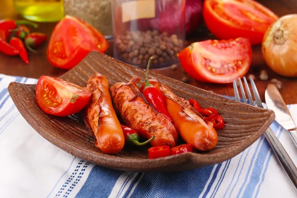 Salsichas deliciosas com legumes no prato na mesa de madeira close-up — Fotografia de Stock