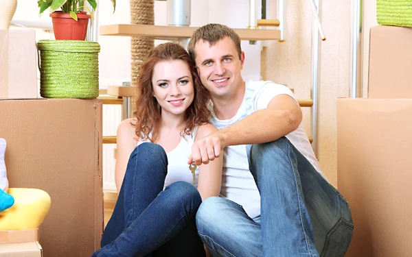 Jovem casal sentado em nova casa no fundo escada — Fotografia de Stock