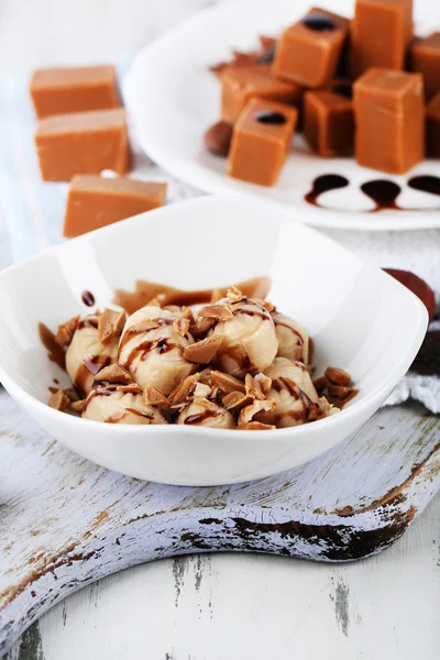 Many toffee on plate and in bowl on napkin on board close-up — Stock Photo, Image