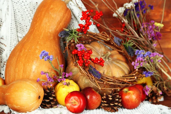 Composition automnale de pommes, citrouilles, fleurs et branches sèches sur table en bois sur fond en bois — Photo