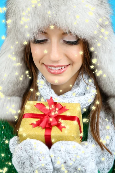 Şapka hediye üzerinde mavi arka plan ile gülümseyen kız güzel — Stok fotoğraf