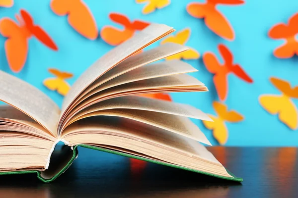 Opened book on wooden table on butterflies background — Stock Photo, Image