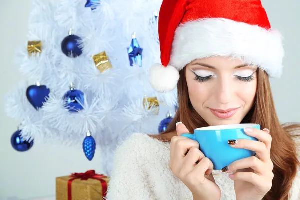 Hermosa chica sonriente cerca del árbol de Navidad con taza — Foto de Stock