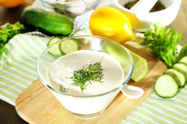 Komkommer yoghurt in glazen kom, op kleur servet, op houten achtergrond — Stockfoto