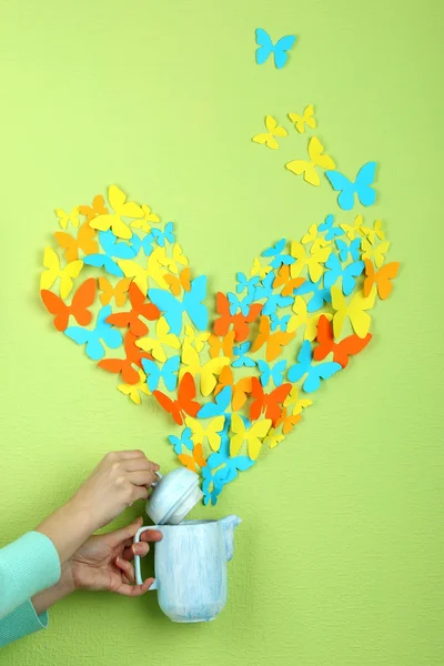 Paper butterflies fly out of teapot on green wall background — Stock Photo, Image