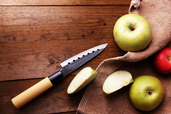 Кухонний ніж і яблука на дерев'яному фоні — стокове фото