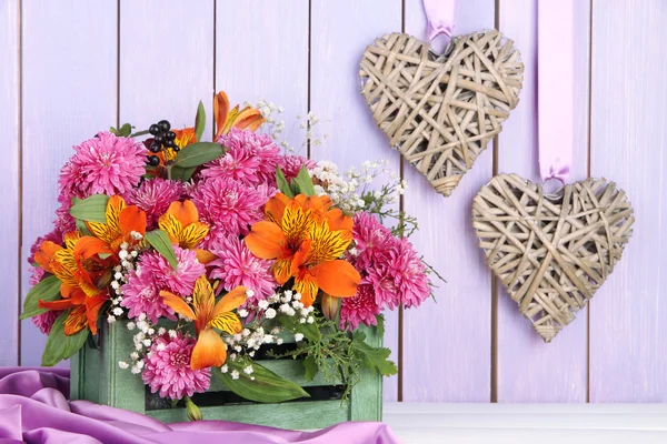 Composition de fleurs dans une caisse avec des cœurs décoratifs sur la table sur fond en bois — Photo