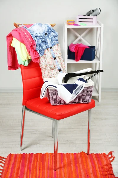 Heap of clothes on color chair, on gray background — Stock Photo, Image