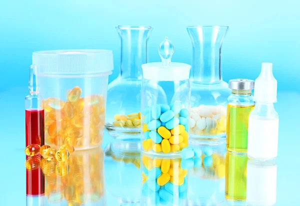 Botellas médicas y pastillas sobre fondo azul — Foto de Stock