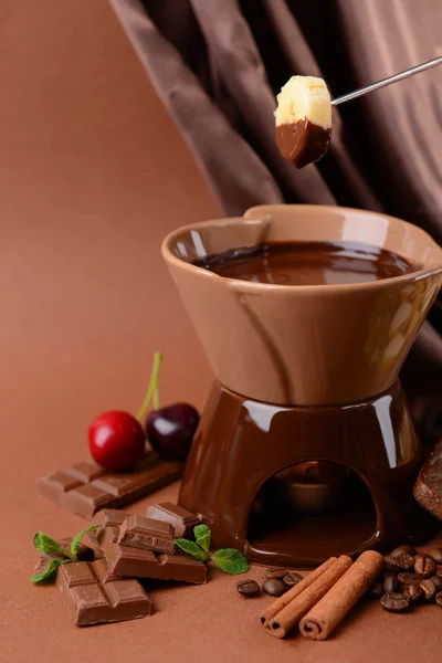 Fondue de chocolate com frutas, em fundo marrom — Fotografia de Stock