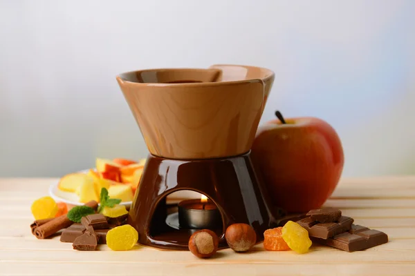 Chocolate fondue with fruits, on wooden table, on light background — Stock Photo, Image