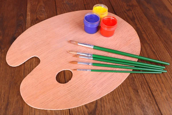 Holzkunstpalette mit Farbe und Pinsel auf dem Tisch Nahaufnahme — Stockfoto