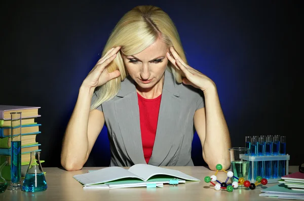 Müder Chemielehrer sitzt am Tisch vor dunklem Hintergrund — Stockfoto