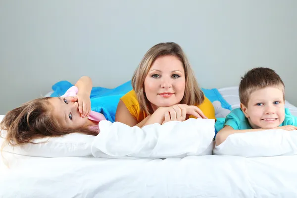 Little children with mom lying in bed — Stock Photo, Image