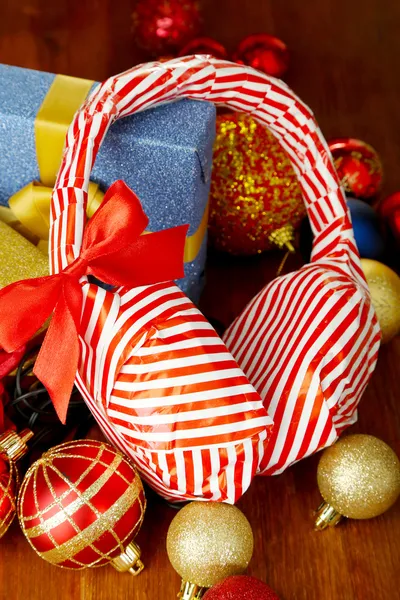 Kopfhörer in Geschenkpapier verpackt mit Geschenken auf Holztisch in Großaufnahme — Stockfoto