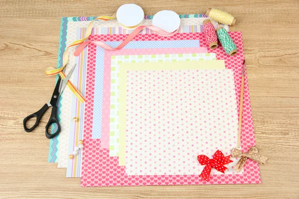 Papier voor scrapbooking en hulpmiddelen voor op houten tafel — Stockfoto