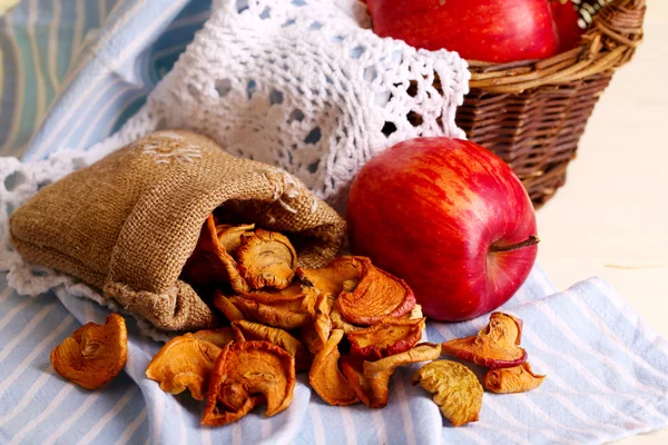 Pommes sèches et pommes fraîches, sur serviette, sur fond de bois blanc — Photo