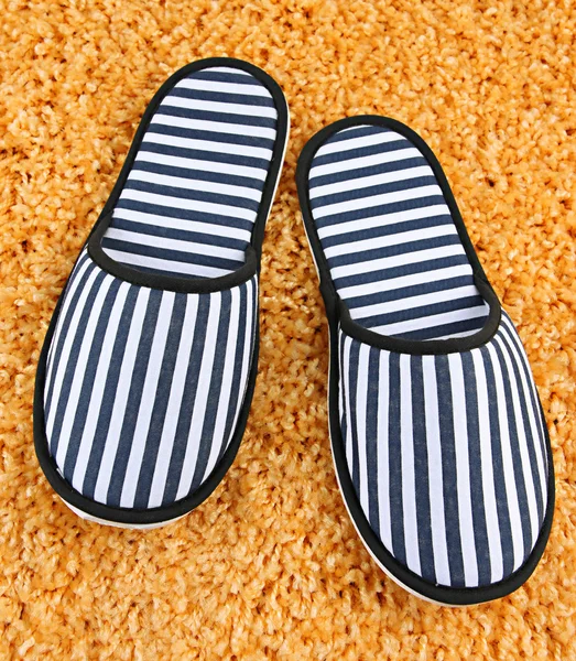 Pantofole a strisce su sfondo tappeto — Foto Stock