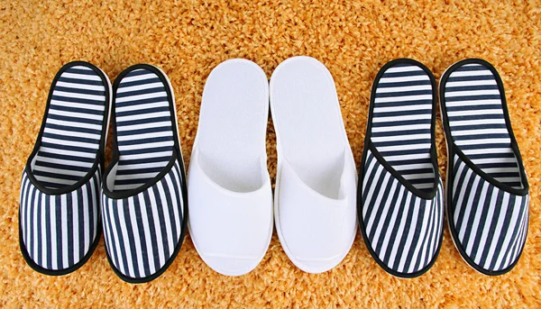 Striped and white slippers on carpet background — Stock Photo, Image