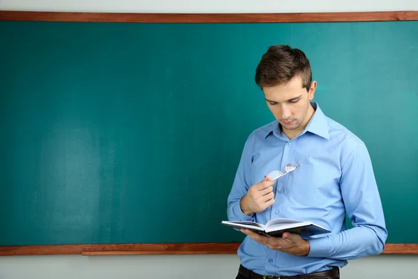 Jonge leraar in de buurt van schoolbord in school klas — Stockfoto