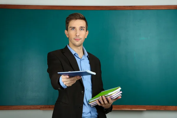 Jonge leraar in de buurt van schoolbord in school klas — Stockfoto