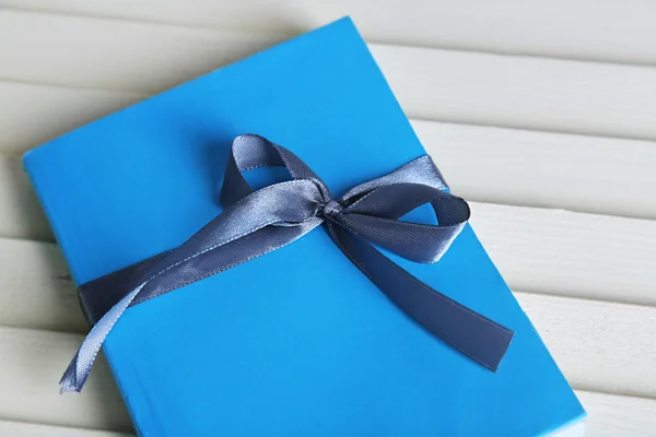 Book wrapped with color ribbon, on wooden background — Stock Photo, Image