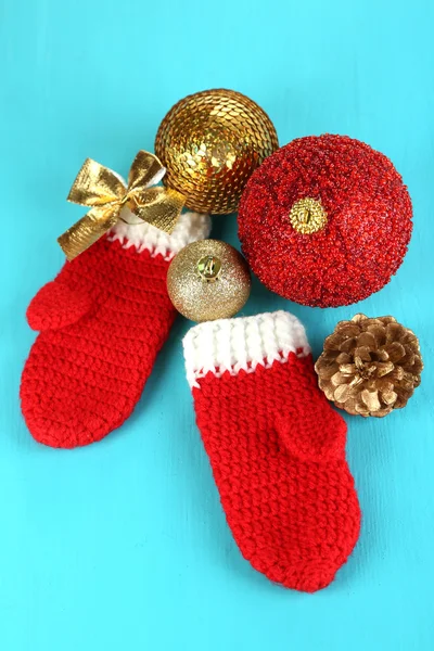 Manoplas rojas de invierno con juguetes de Navidad en mesa de madera azul — Foto de Stock