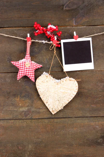 Coração decorativo, estrela e papel fotográfico vazio na corda, no fundo de madeira — Fotografia de Stock
