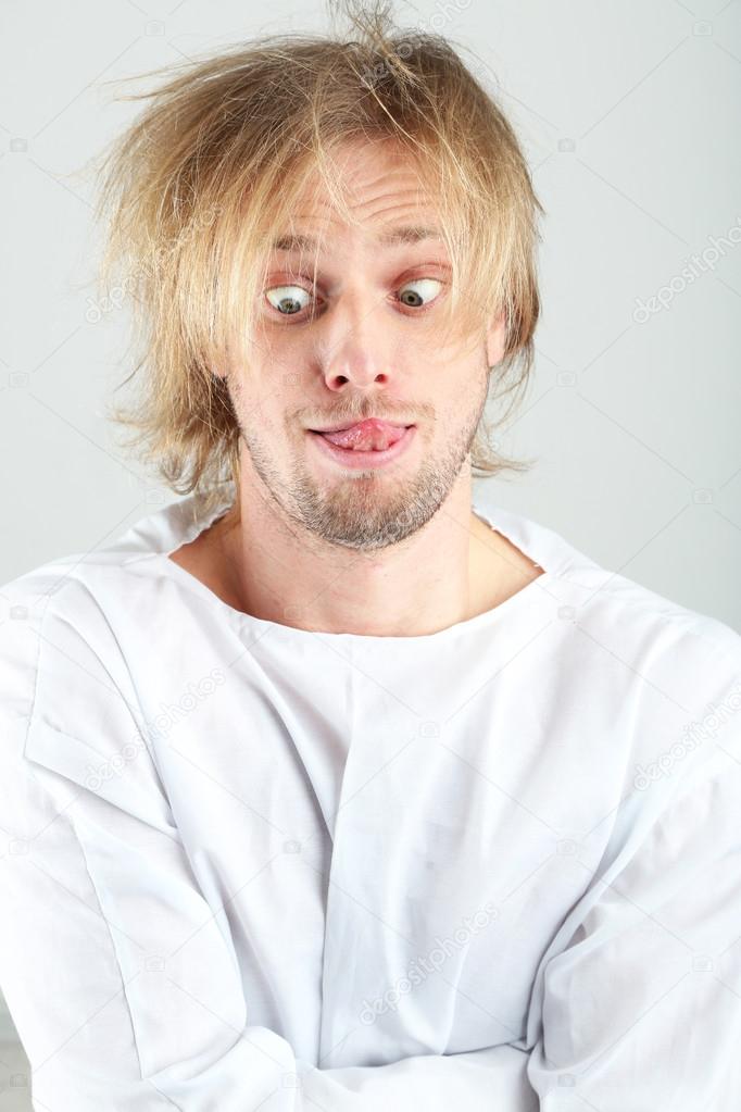 Mentally ill man in strait-jacket on gray background