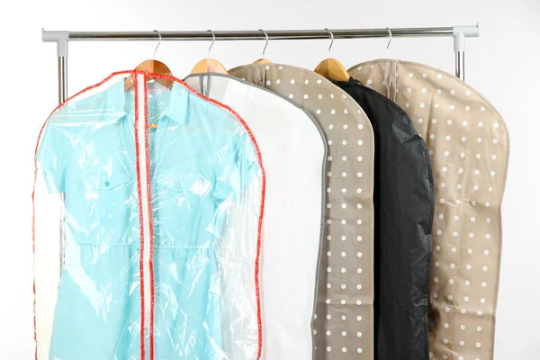 Vêtements dans des étuis pour le stockage sur cintres, sur fond gris — Photo