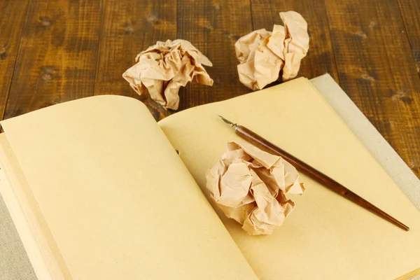 Bolas de papel enrugadas com notebook e caneta de tinta em fundo de madeira — Fotografia de Stock