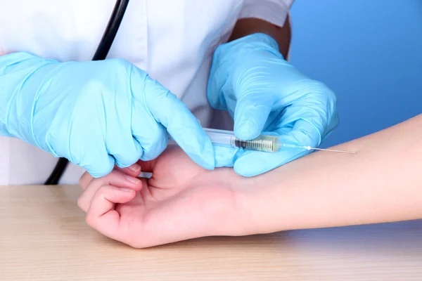 Impfstoffspritze in der Hand auf blauem Hintergrund — Stockfoto