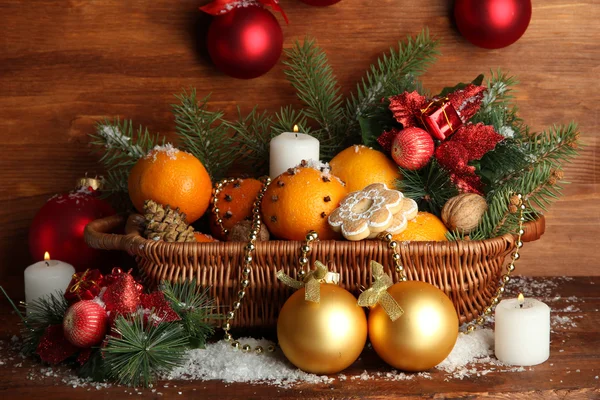 Christmas composition in basket with oranges and fir tree, on wooden background — Stock Photo, Image