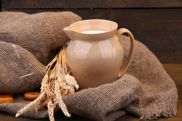 Tarro de leche, sabrosos bagels y espiguillas sobre fondo de madera — Foto de Stock