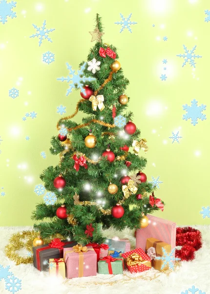 Украшенная елка с подарками на зеленом фоне стены — стоковое фото
