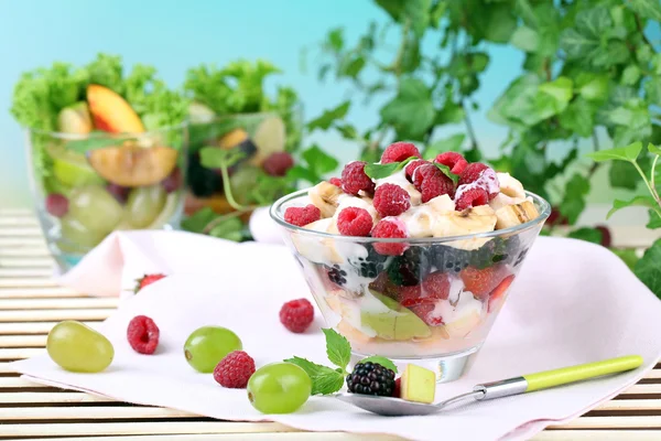 Insalata di frutta in ciotola, su tavolo di legno, su sfondo brillante — Foto Stock