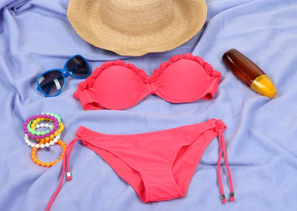 Swimsuit and beach items on purple background — Stock Photo, Image