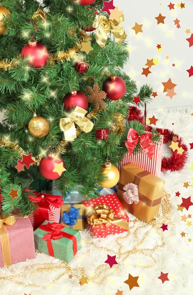 Decorated Christmas tree with gifts on grey wall background — Stock Photo, Image