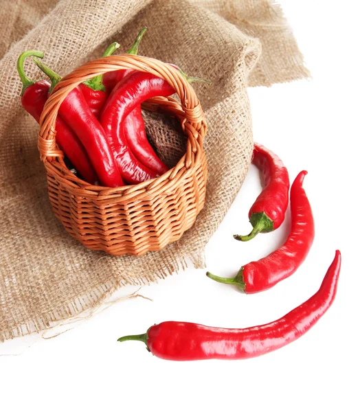 Rode hete chili peppers in rieten mand, op rouwgewaad, geïsoleerd op wit — Stockfoto