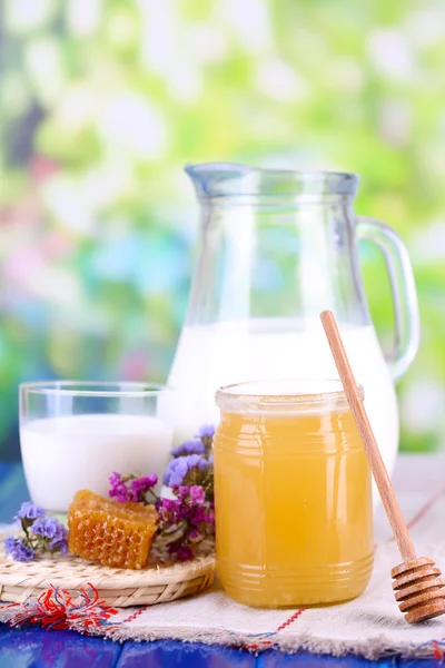 Honig und Milch auf Holztisch vor natürlichem Hintergrund — Stockfoto