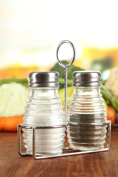 Salt and pepper mills, on wooden table, on bright background — Stock Photo, Image