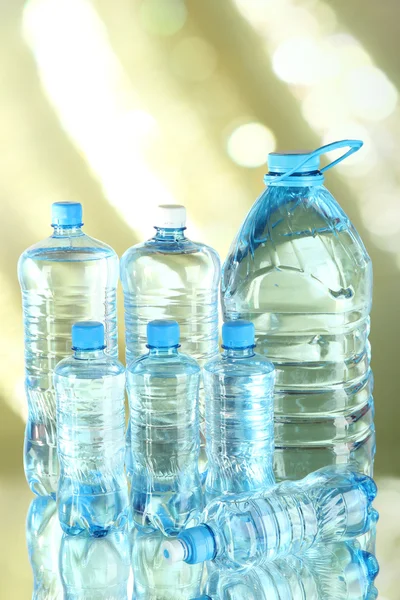 Água em diferentes garrafas no fundo de luz — Fotografia de Stock